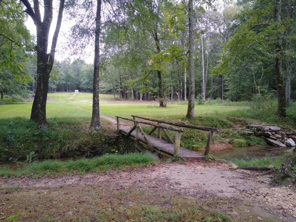 Pedestrian bridge across a small creek on the Shiloh Battlefield. Battery of two canon in the background